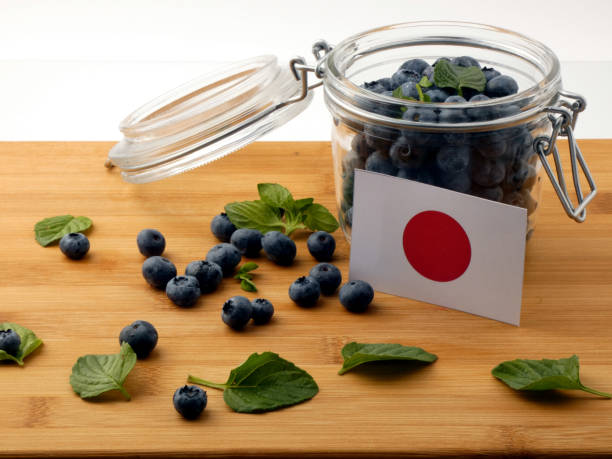 istock Japanese flag on a wooden plank with blueberries isolated on white 842820092