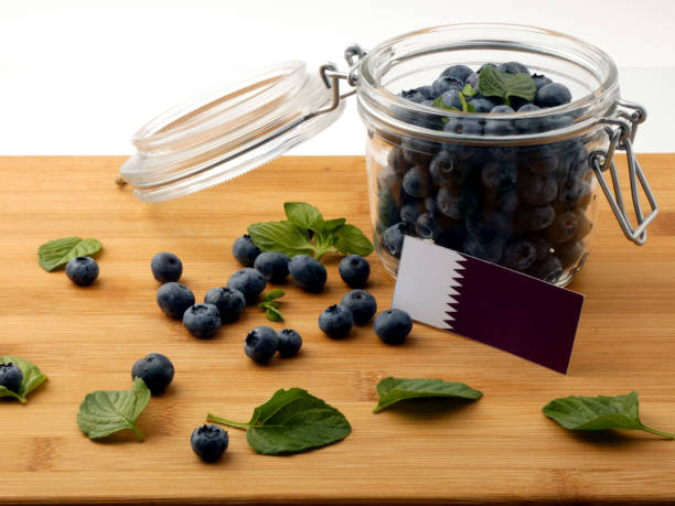 istock Qatari flag on a wooden plank with blueberries isolated on white 842820278