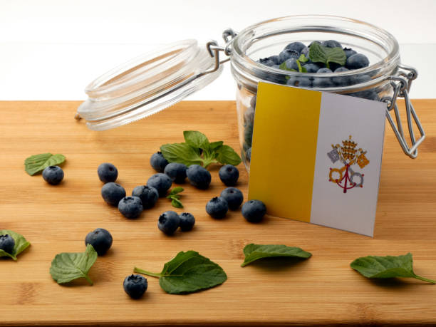 istock Vatican flag on a wooden plank with blueberries isolated on white 842820864