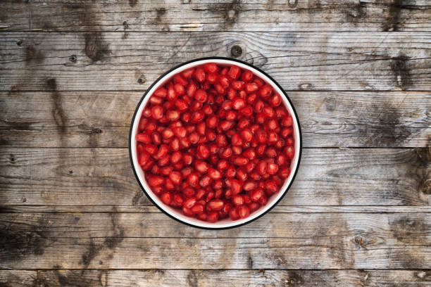 istock Pomegranate seeds bowl on wood background from directly above 842821356