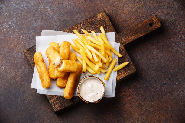 Fish fingers and Chips with tartar sauce Fish fingers and Chips british fast food with tartar sauce on dark background fish stick stock pictures, royalty-free photos & images