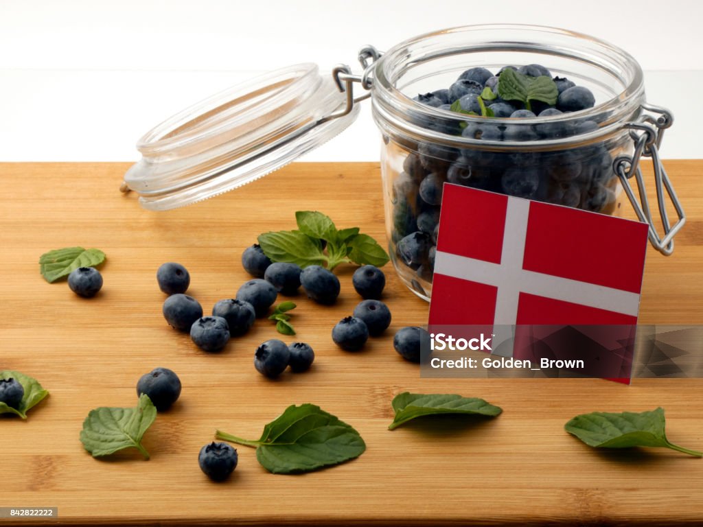 Bandeira dinamarquesa numa prancha de madeira com mirtilos isolado no branco - Foto de stock de Alimentação Saudável royalty-free