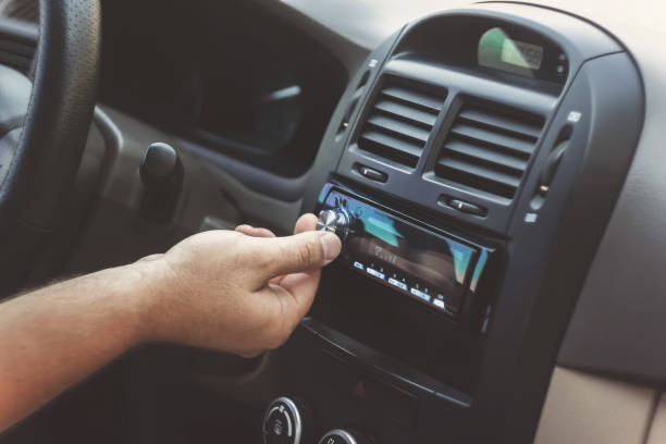 man's hand twists the volume in a retro toning car - car dealership audio imagens e fotografias de stock