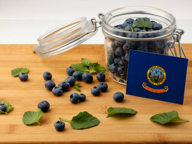 istock Idaho flag on a wooden plank with blueberries isolated on white 842832588
