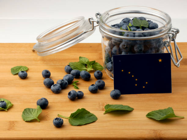istock Alaska flag on a wooden plank with blueberries isolated on white 842832730