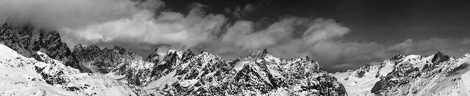 Black and white large panoramic view on snow mountains in haze at sunny day. Caucasus Mountains. Svaneti region of Georgia.
