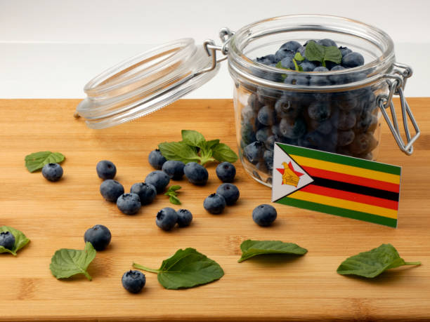 Zimbabwe flag on a wooden plank with blueberries isolated on white