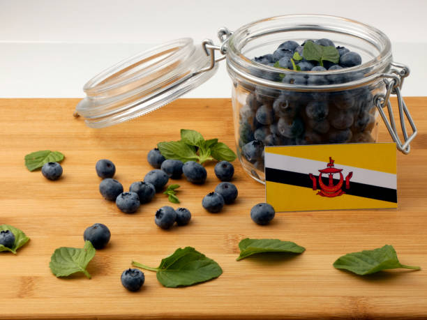 istock Brunei flag on a wooden plank with blueberries isolated on white 842841110