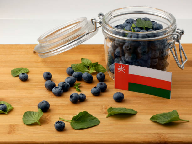 istock Omani flag on a wooden plank with blueberries isolated on white 842844340