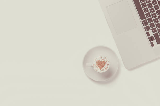 istock Cup of cappuccino with heart shape and white laptop 842848548
