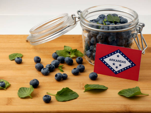 istock Arkansas flag on a wooden plank with blueberries isolated on white 842849326