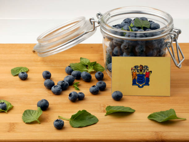 New Jersey flag on a wooden plank with blueberries isolated on white stock photo