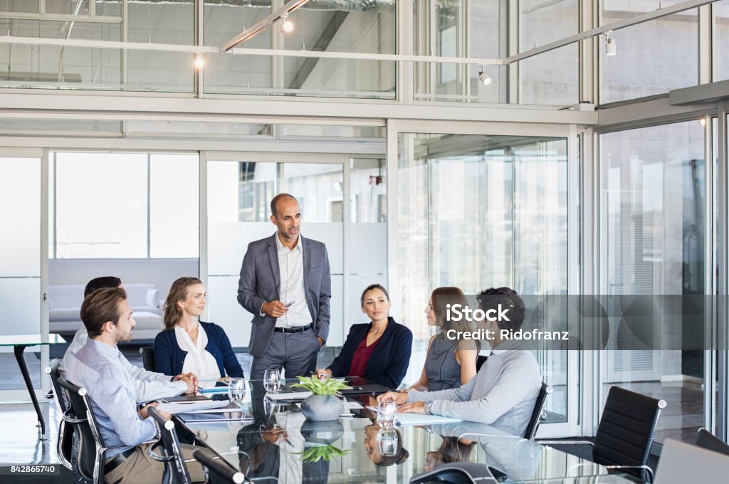 Business team in a meeting Human resource manager training people about company and future prospects. Group of businesspeople sitting in meeting room and listening to the speaker. Leader man training his work group in a conference room. Meeting Stock Photo