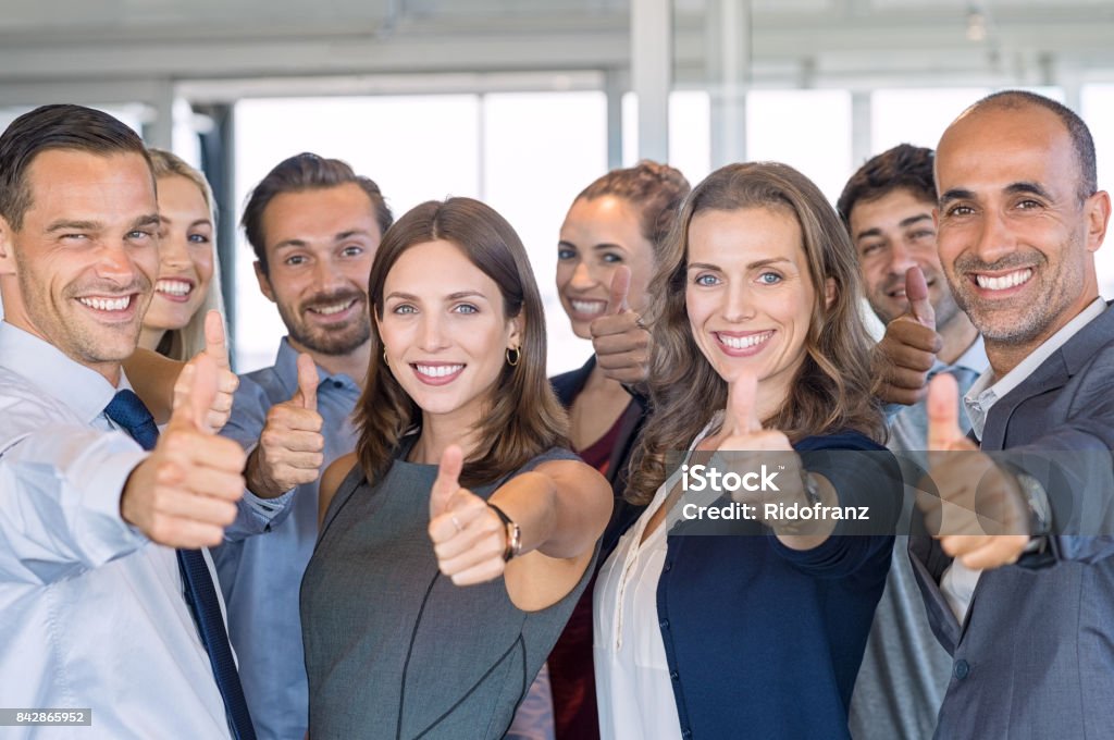 Successful business team Group of happy business people showing sign of success. Successful business team showing thumbs up sign and looking at camera. Smiling businessmen and businesswomen cheering at office. Thumbs Up Stock Photo