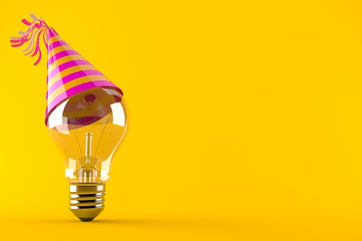 Light bulb with party hat isolated on orange background
