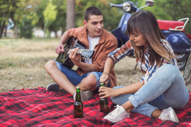 istock Couple enjoying in park with guitar and beer 842873458