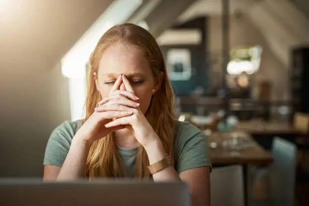 Cropped shot of a young woman looking stressed while sitting in front of her laptop