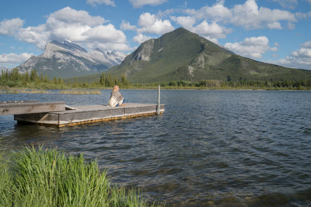 istock Female sitting on lake pier enjoys nature 842883254