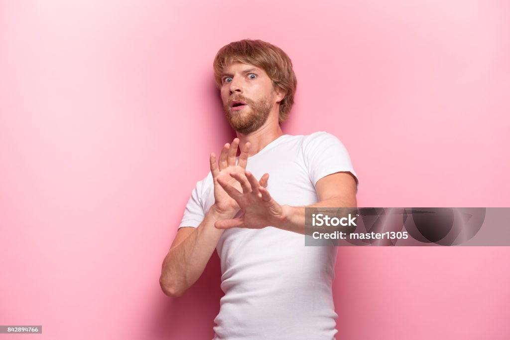 Crazy desperate good-looking man being shocked looking at camera with wide opened mouth Crazy desperate good-looking man being shocked looking at camera with wide opened mouth and bugged eyes shouting with horror. Anxious male trembling with fear. Negative emotions and feelings concept. Human Face Stock Photo