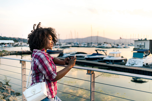 Woman looking at yachts on harbor at sunset.