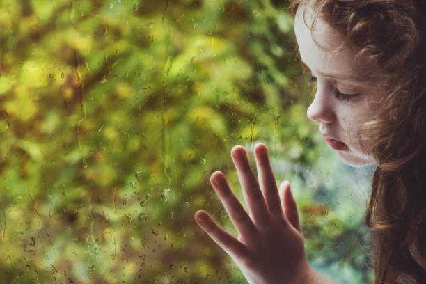 istock Sad curly little girl looking out the rain drop window 842903156