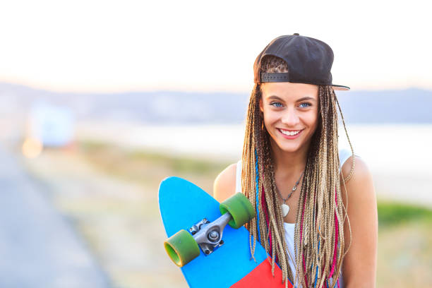 Woman with skateboard standing on road nera the sea.