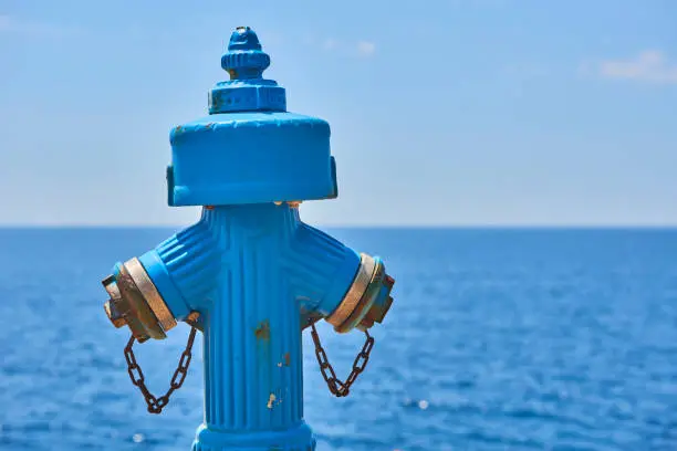 Blue grungy hydrant with blue calm sea at backgrounds. Romance background. Romantic honeymoon vacation idea.