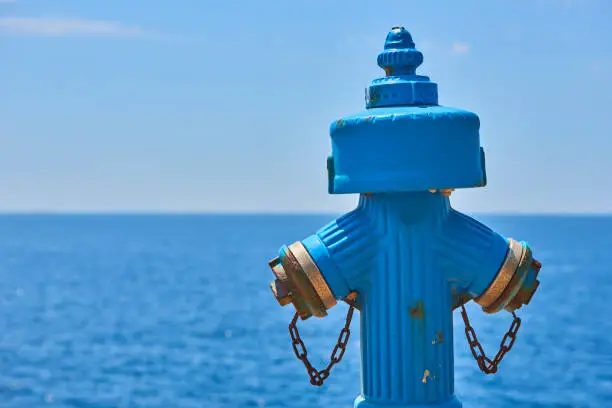 Blue grungy hydrant with blue calm sea at backgrounds. Romance background. Romantic honeymoon vacation idea.