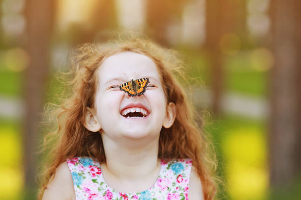 Funny laughing curly girl with a butterfly on his nose. Funny laughing curly girl with a butterfly on his nose. Healthy smile with white teeth. Free breathing concept. children laughing stock pictures, royalty-free photos & images