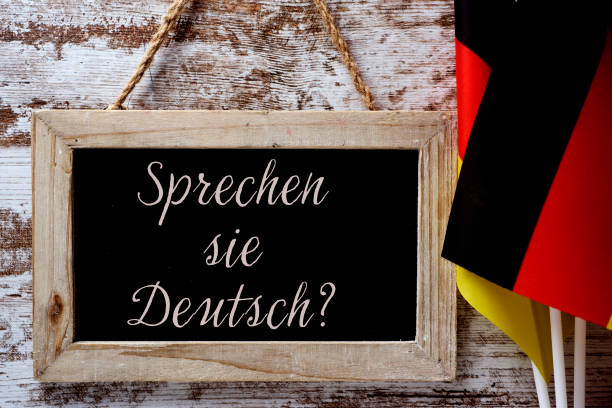 question do you speak German? in German a wooden-framed chalkboard with the question Sprechen sie Deutsch? do you speak German? written in German, and some flags of Germany against a rustic wooden background german language photos stock pictures, royalty-free photos & images