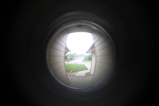 The World on the Other Side The lens of a camera is looking through a door's peephole and sees a whole world on the other side. peep hole stock pictures, royalty-free photos & images