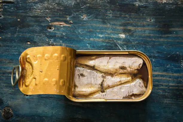Photo of Canned fish on a rustic blu table
