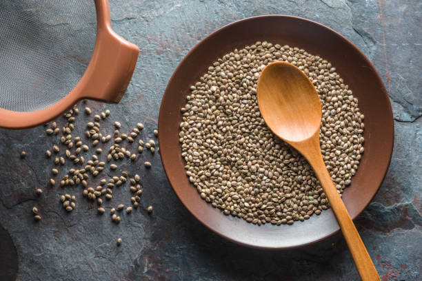 istock Hemp seeds on a plate, a sieve on a gray blue stone 842979728