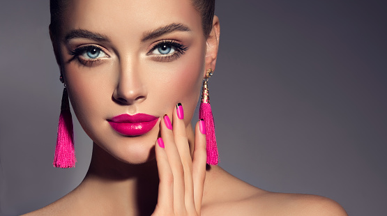 Misty look of perfect model. Pretty  blue eyed model dressed in tassel-earrings is demonstrating an elegant, attractive make up and purple manicure.