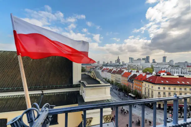 Photo of Poland Flag in Blue Sky and Warsaw in background