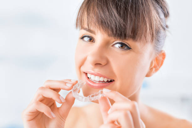Beautiful smile and white teeth of a young woman. Woman wearing orthodontic silicone trainer. Invisible braces aligner. Mobile orthodontic appliance for dental correction. dental aligner photos stock pictures, royalty-free photos & images