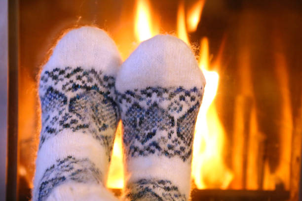 istock Feet in wool socks warming at the fireplace 843009440