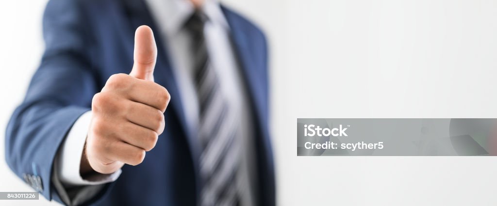 Business man shows thumb up sign gesture. Business man shows thumb up sign gesture. Isolated on grey background. Thumbs Up Stock Photo