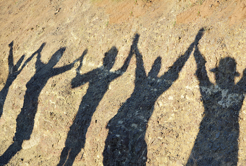 Unity and success and friendship concepts, shadow of group of women holding hands after finishing hiking in the mountain