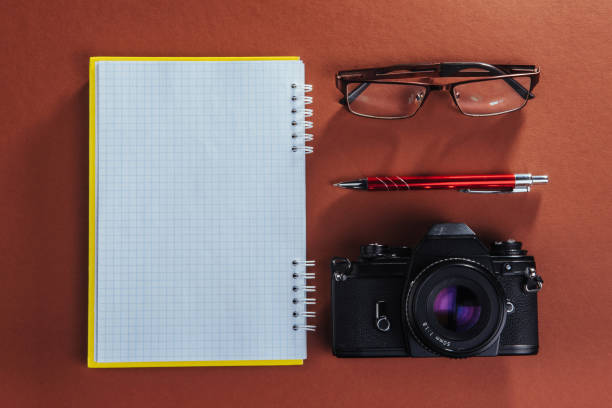 istock camera, glasses and notepad and pencil on a brown wooden background 843012984