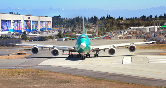 Everett, Washington, USA - July 31, 2017 - Boeing 4-engine double deck 747 jet airplane being tested on the runway at the Boeing factory located in Everett, Washington USA. The planes in production are wrapped in green coating.