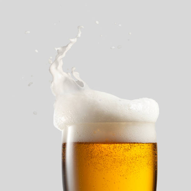 Close-up of cold beer with foam Close-up of cold beer with foam and splash on a gray background frothy drink stock pictures, royalty-free photos & images