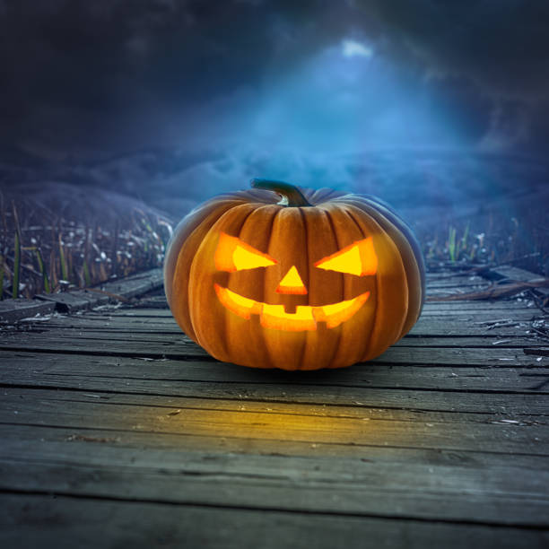 istock Spooky Halloween pumpkin on wooden path at night 843030434