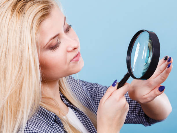 istock Woman looking at nails through magnifying glass 843037738