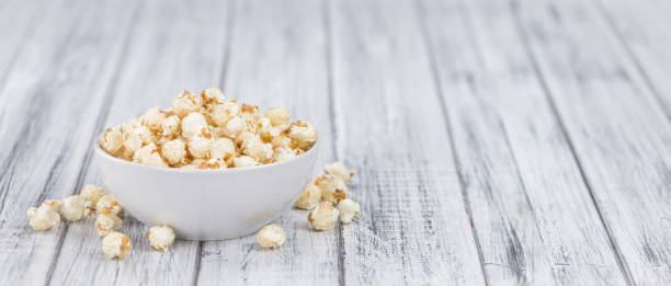istock Portion of Popcorn on wooden background, selective focus 843042074
