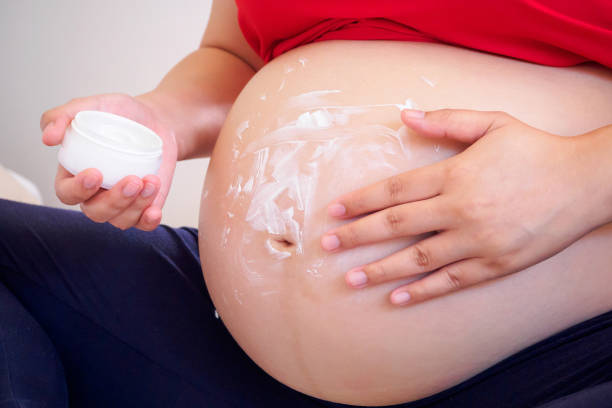 istock Pregnant Woman applying stretch marks cream on her belly 843052038