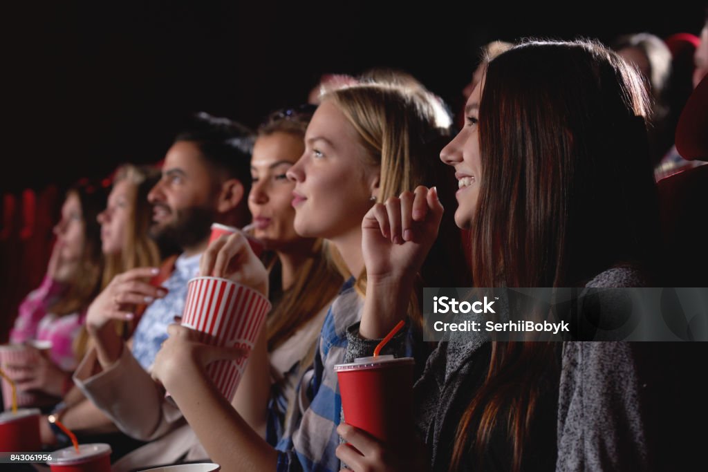 Group of people enjoying movie at the cinema Group of female friends laughing and smiling watching a film together at the movie theatre snacks popcorn entertainment people lifestyle leisure friendship concept. Movie Theater Stock Photo