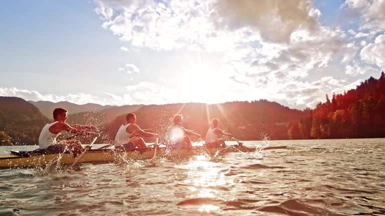 SLO MO Male athletes rowing on a lake in sunshine