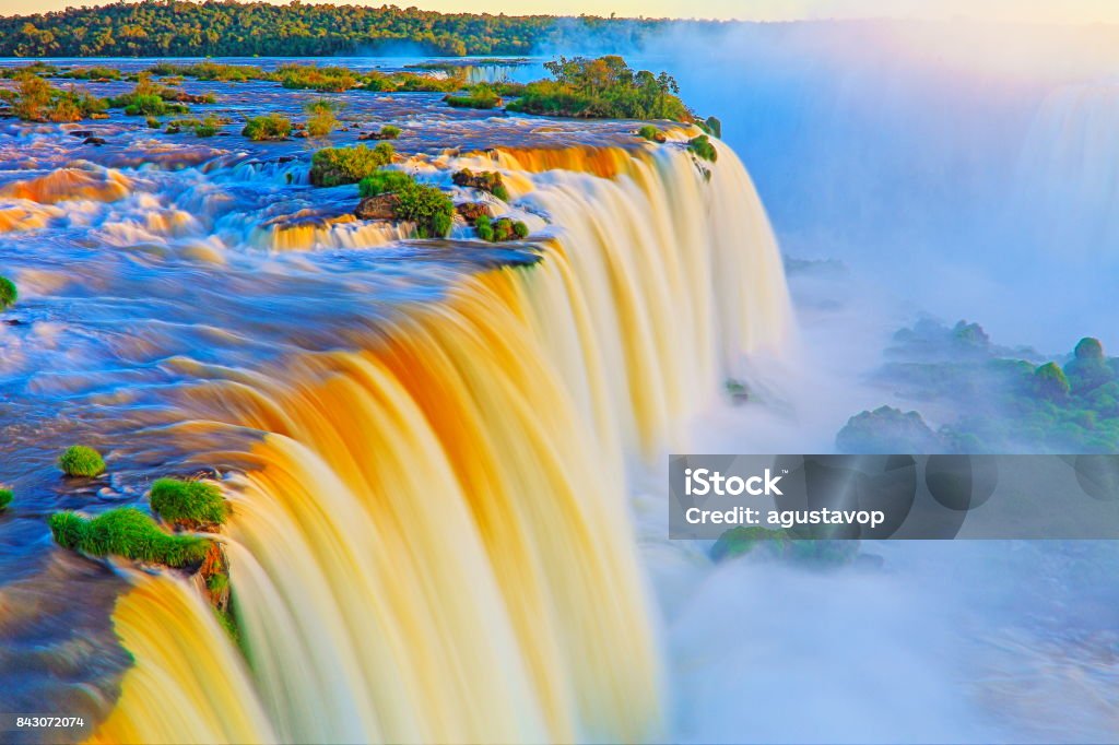 Impressive Iguacu falls landscape, blurred motion from long exposure at dramatic sunset - Idyllic Devil's Throat - international border of Brazilian Foz do Iguacu, Parana, Argentina Puerto Iguazu, Misiones and Paraguay - South America Impressive Iguacu falls, one of the most beautiful waterfalls in the world and one of the seven Wonders of Nature, blurred motion from long exposure at dramatic sunset - Idyllic Devil's Throat - international border of Brazilian Foz do Iguacu city, Parana State, Argentina Puerto Iguazu city, Misiones province and Paraguay - rainforest landscape panorama, South America Paraguay Stock Photo