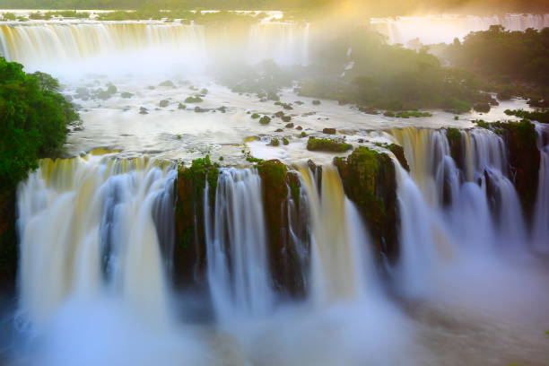 Impressive Iguacu falls landscape, blurred motion from long exposure at dramatic sunset - Idyllic Devil's Throat - international border of Brazilian Foz do Iguacu, Parana, Argentina Puerto Iguazu, Misiones and Paraguay - South America Impressive Iguacu falls, one of the most beautiful waterfalls in the world and one of the seven Wonders of Nature, blurred motion from long exposure at dramatic sunset - Idyllic Devil's Throat - international border of Brazilian Foz do Iguacu city, Parana State, Argentina Puerto Iguazu city, Misiones province and Paraguay - rainforest landscape panorama, South America misiones province stock pictures, royalty-free photos & images